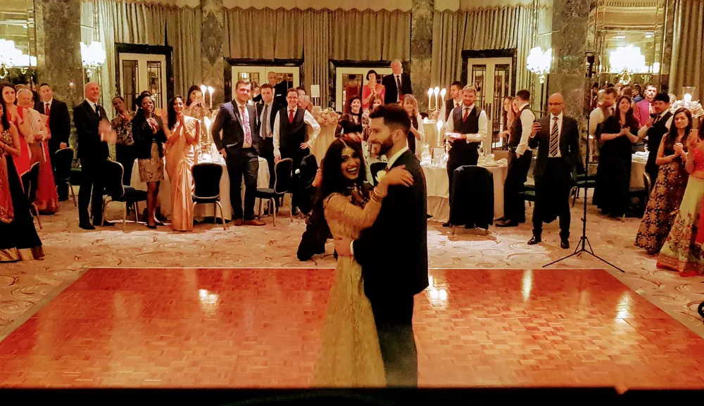 A couple's first dance on the parquet floor of a grand ballroom