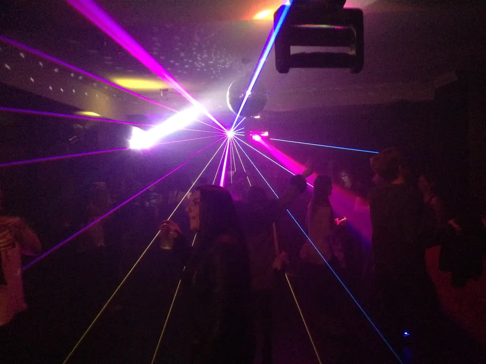 Lasers and a mirror ball over the dance floor late in the night