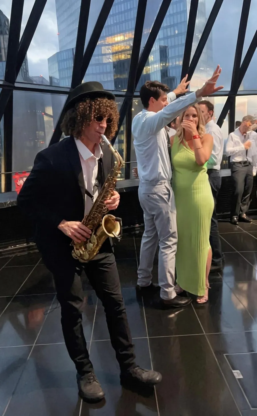 Live saxophonist playing among the guests at an evening city event